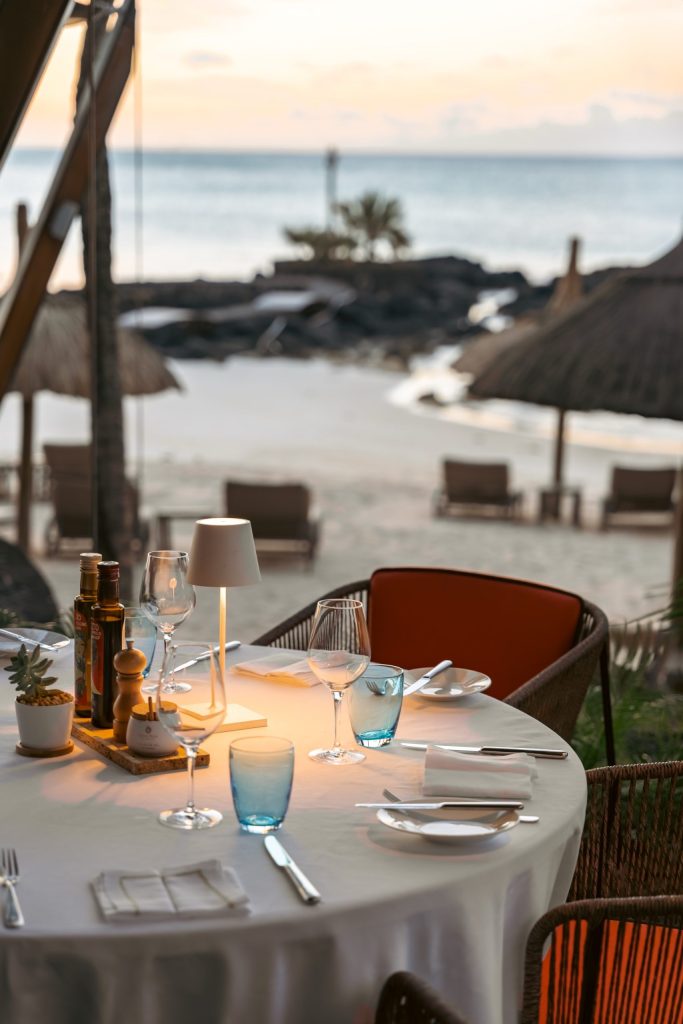 Tisch im Restaurant Grand Sable mit weißem Tischtuch, Rattanstühlen und Blick auf Strand und Meer in Mauritius