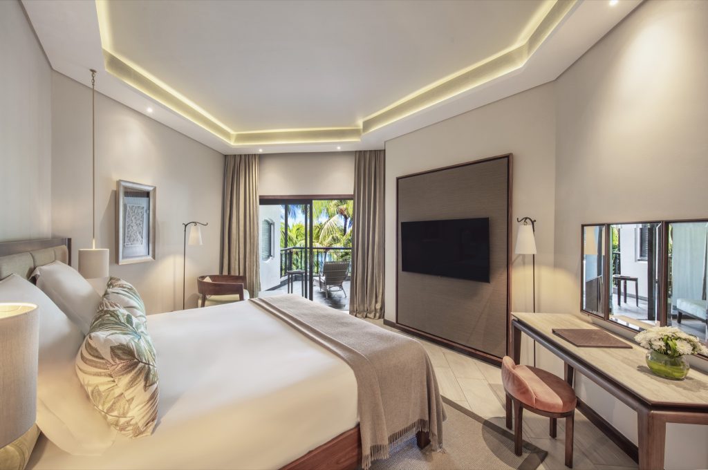 Modernes Penthouse Zimmer mit Doppelbett, Holzmöbeln, Balkon und Blick auf Palmen in Mauritius