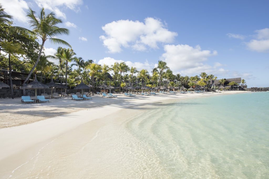 Tropischer Strand mit weißem Sand, Palmen und Liegestühlen unter Strohsonnenschirmen am Royal Palm Beachcomber Luxury