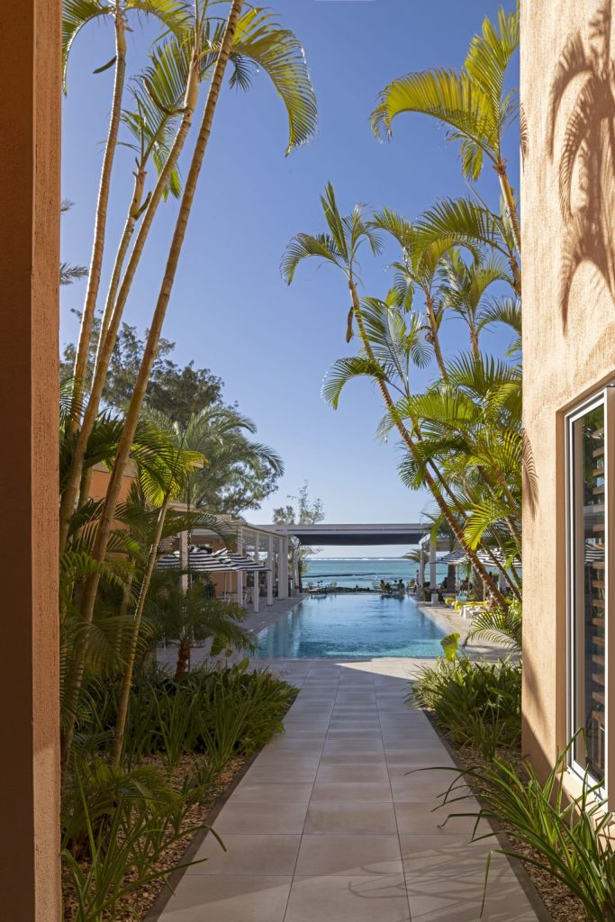Blick durch Flur mit Palmen auf Pool und Meer am Salt of Palmar auf Mauritius