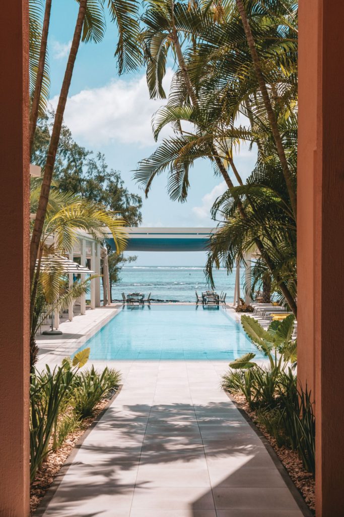 Poolbereich mit hellen Fliesen, Palmen und Meerblick im Salt of Palmar auf Mauritius