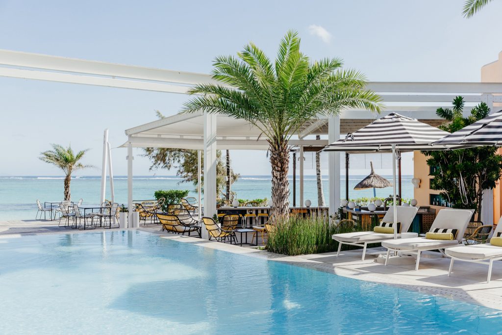 Poolbereich im Salt of Palmar mit türkisfarbenem Wasser, weißen Sonnenliegen, gestreiften Sonnenschirmen und Meereshorizont