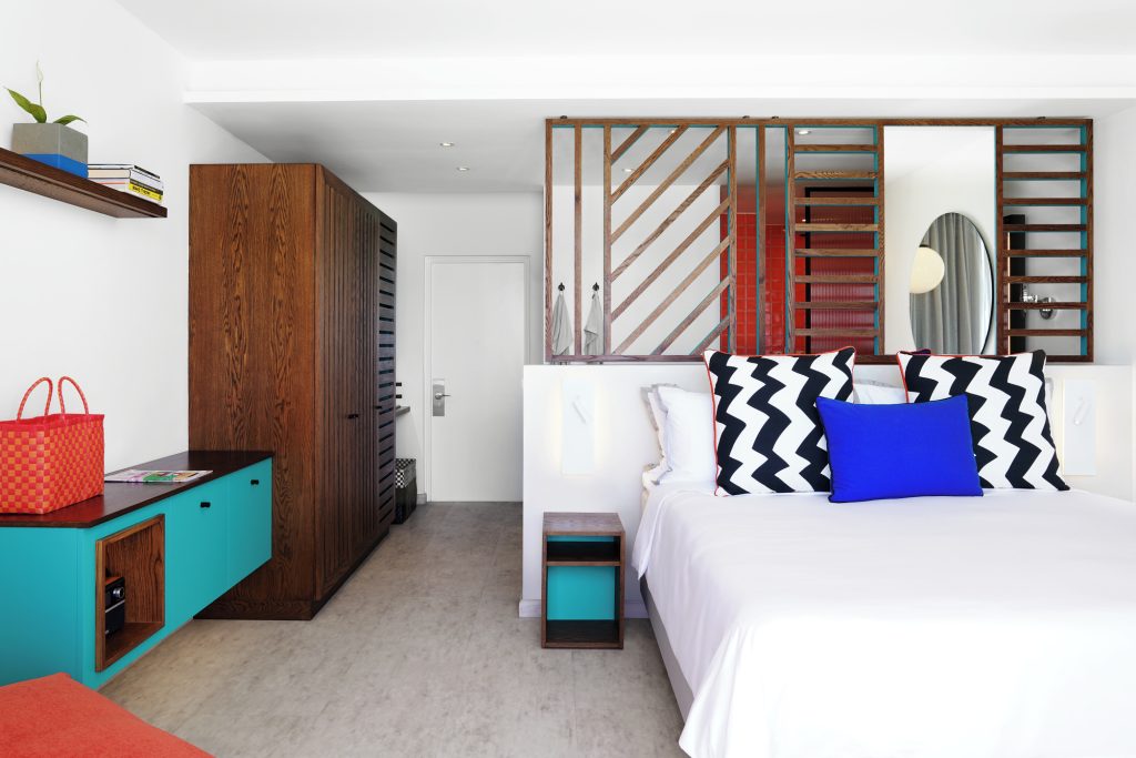 Modernes Hotelzimmer Salt of Palmar Bang on Beach mit weißem Bett, schwarz-weiß gemusterten Kissen und türkisfarbenem.