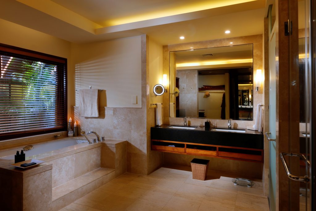 Badezimmer mit großer Badewanne, Doppelwaschbecken, Marmorverkleidung und Fenster
