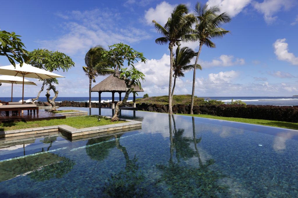Infinity-Pool mit Holzterrasse, Sonnenschirmen und tropischen Bäumen im Shanti Maurice Resort & Spa