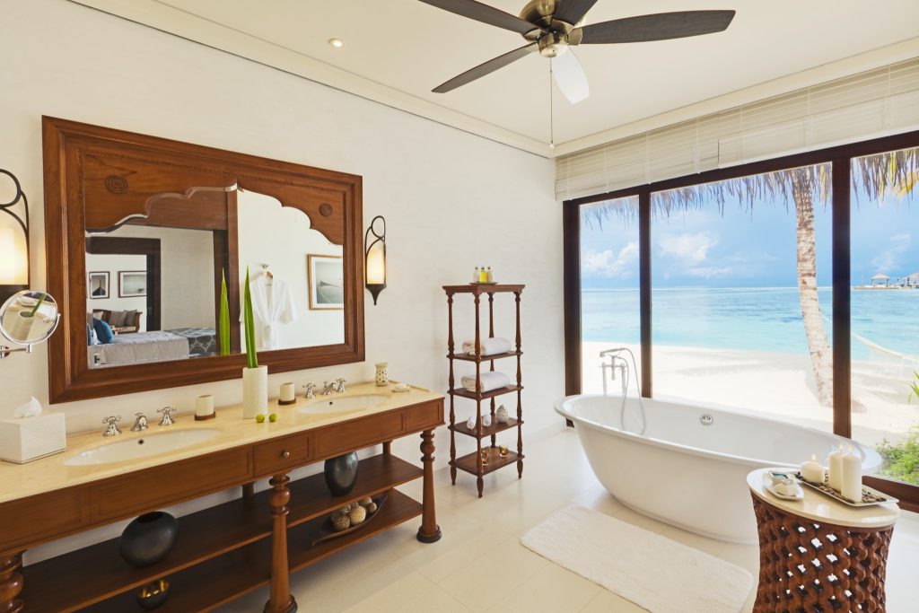 Badezimmer der Beach Villa mit hölzernem Waschtisch, zwei Waschbecken, freistehender Badewanne und Meerblick auf den.