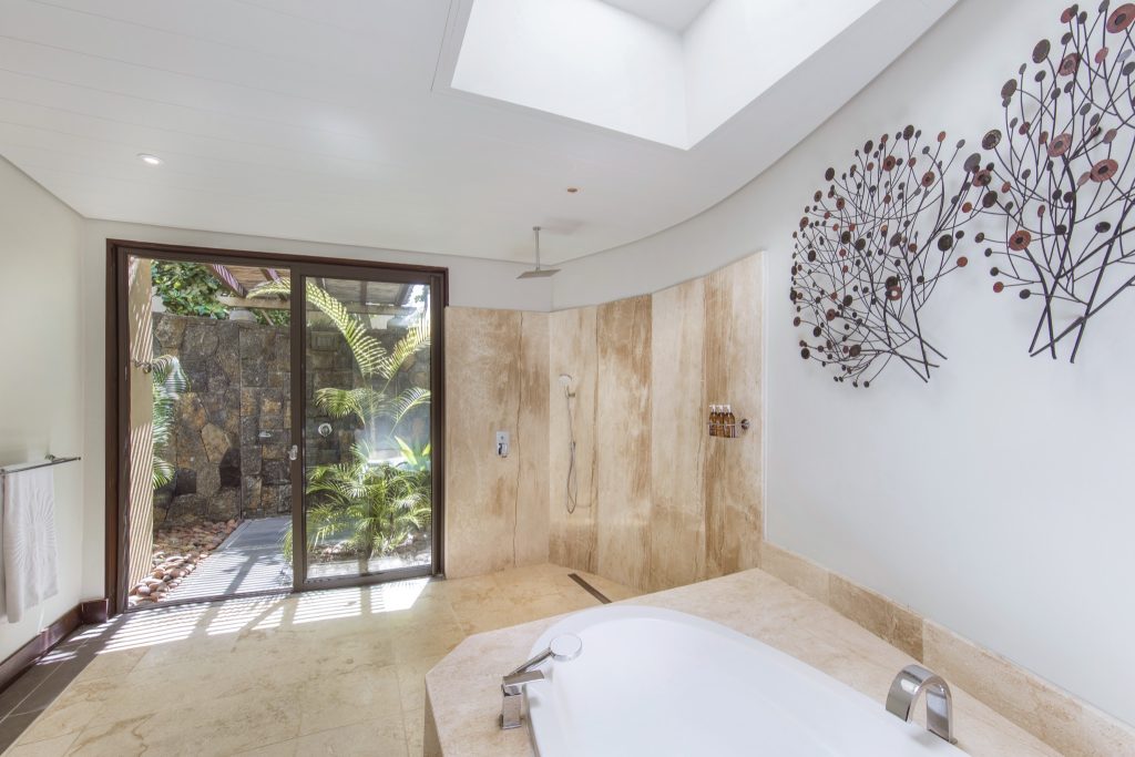 Modernes Badezimmer der Beachfront Suite mit freistehender Badewanne, Natursteindusche und Gartenblick in Mauritius