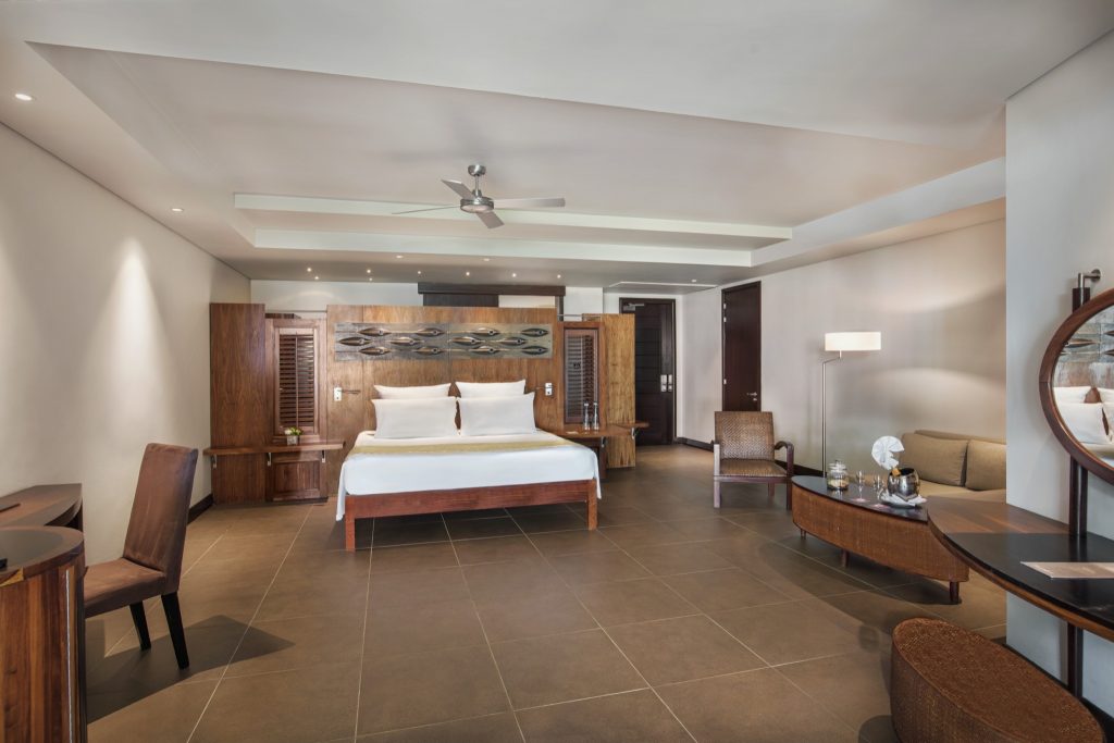 Großes Hotelzimmer der Beachfront Suite mit Doppelbett, dunklen Holzmöbeln und braunen Fliesen