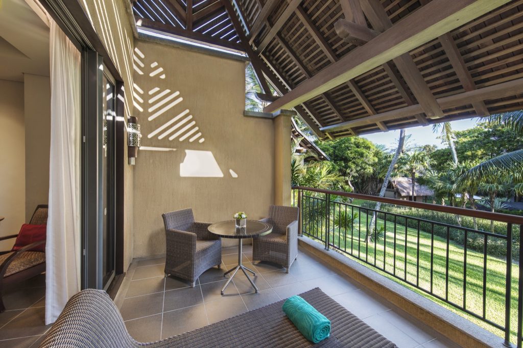 Balkon mit zwei Rattanstühlen und Glastisch, Blick auf grüne Palmenlandschaft im Trou aux Biches Beachcomber Golf Resort &.