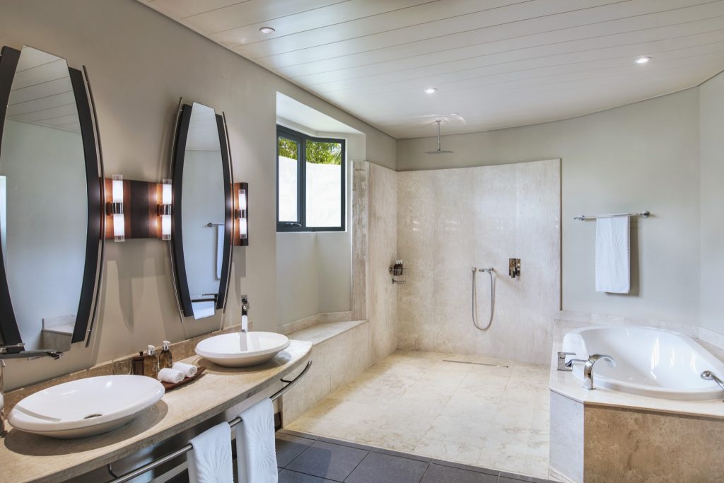 Geräumiges Badezimmer der Junior Suite mit zwei ovalen Spiegeln, Waschbecken, Marmor, Dusche