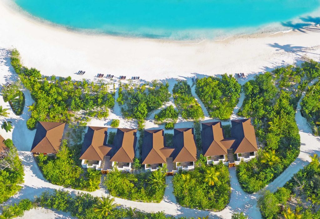 Luftaufnahme der Resort Varu by Atmosphere mit braunen Dächern, Sandwegen, grünem Pflanzenbewuchs und türkisfarbenem Meer