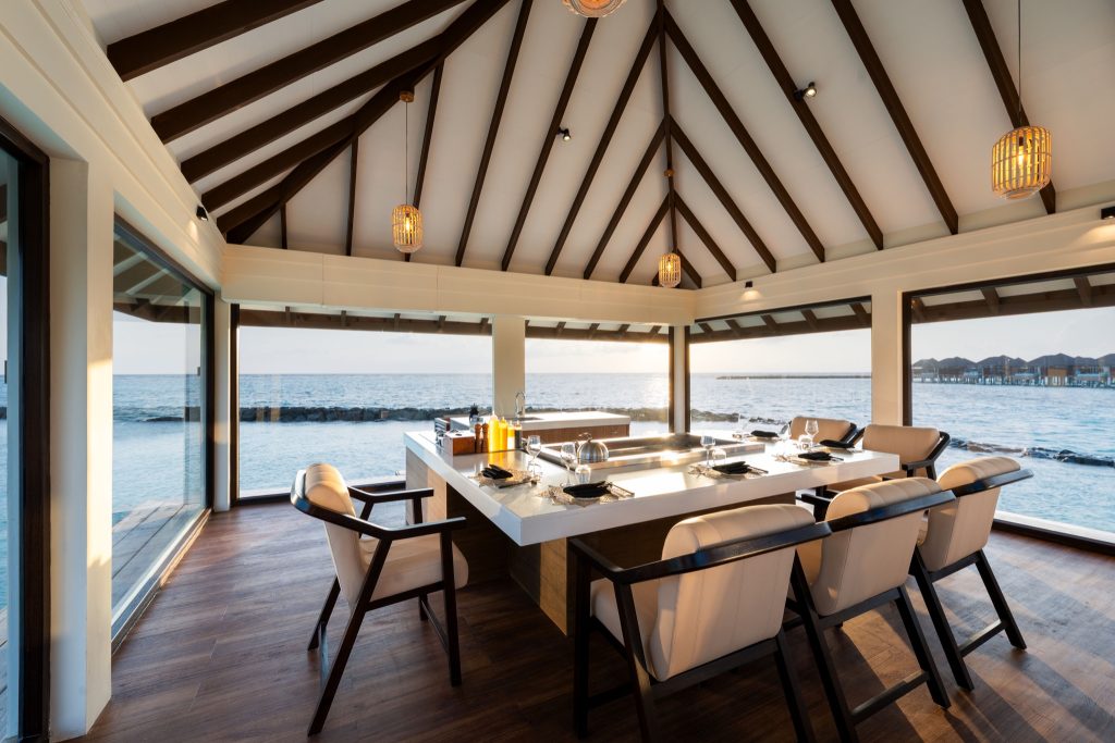Restaurant Teppanyaki mit hellem Holztisch, cremefarbenen Stühlen und Panoramafenstern mit Blick auf das Meer