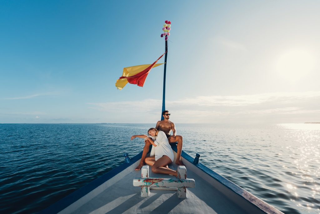 Boot mit blau-weißer bemalter Oberfläche und Mast mit rot-gelber Fahne auf offenem Meer