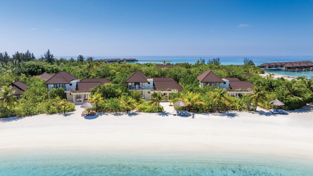 Reihe von Majlis Residence Bungalows mit dunklen Holzdächern und weißen Fassaden am Strand auf den