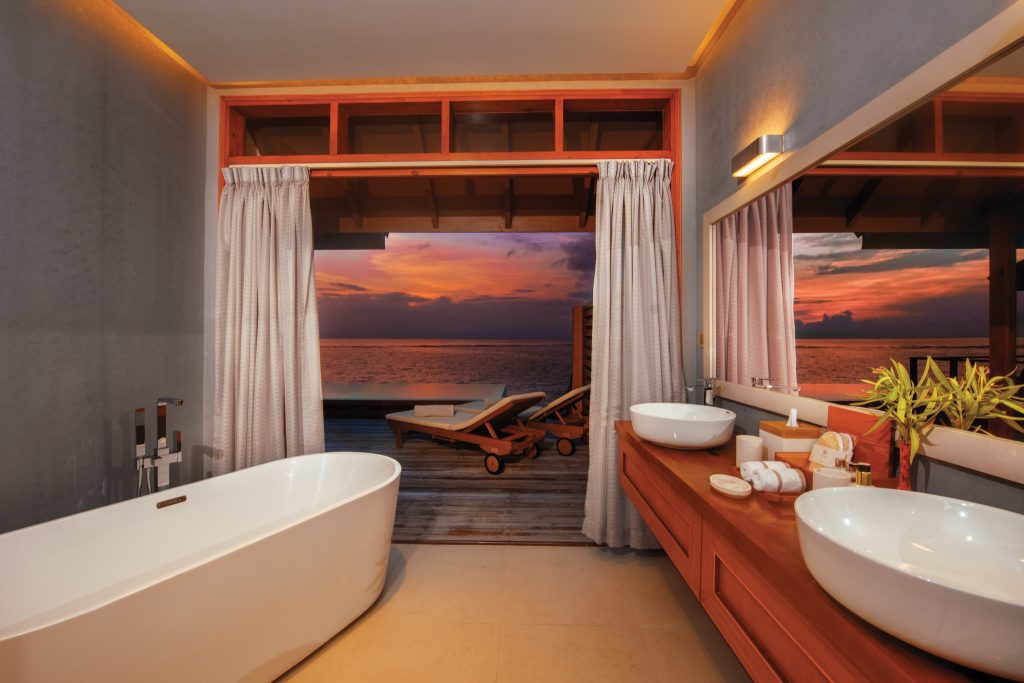 Badezimmer der Water Suite im Varu by Atmosphere mit freistehender Badewanne, Waschtisch und Terrasse mit Meerblick