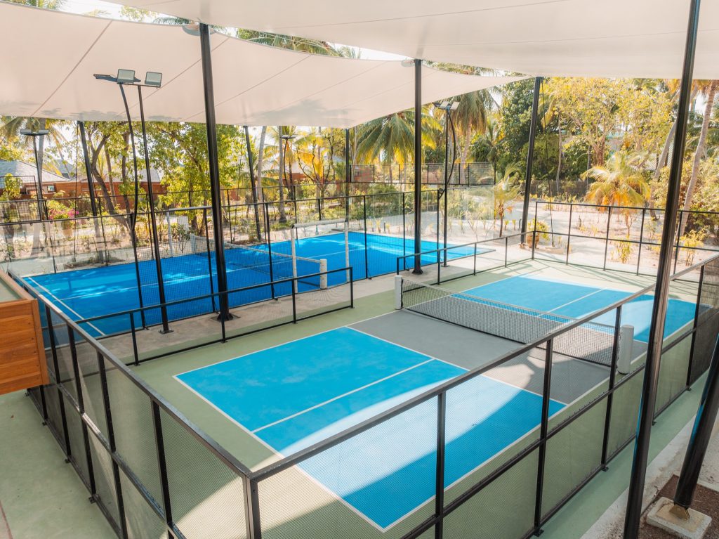 Mehrere Paddle-Tennis Plätze mit blau-grünem Kunststoffbelag und weißem Sonnenschutz im Veligandu Maldives Resort Island