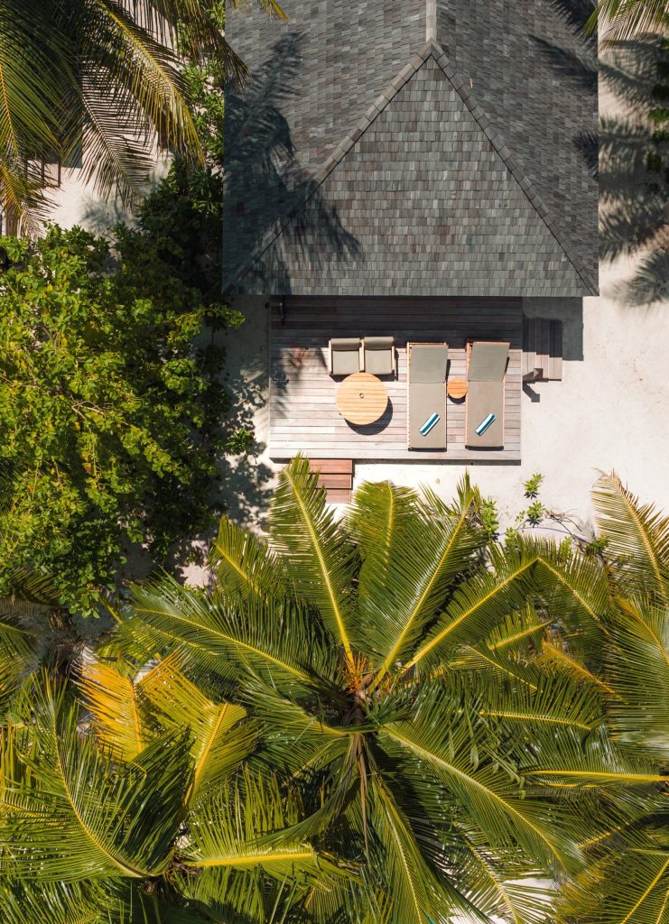 Luftaufnahme der Terrasse der Beach Villa im Veligandu Maldives Resort Island mit zwei grauen Sonnenliegen und Holztisch.
