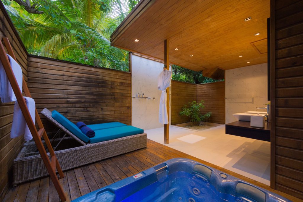 Outdoor Badezimmer mit Whirlpool, Liege, Dusche mit marmorierten Fliesen und dunklen Holzwänden