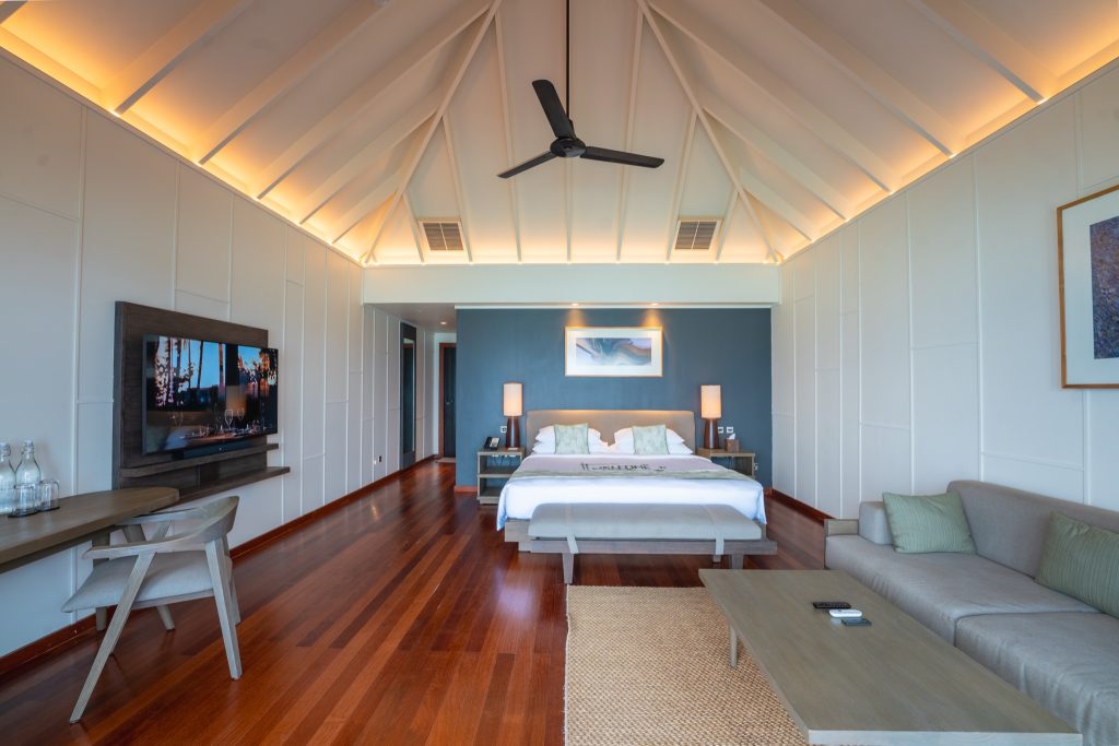 Modernes Hotelzimmer mit Doppelbett, dunkelblauer Akzentwand, Holzfußboden, Sitzgruppe