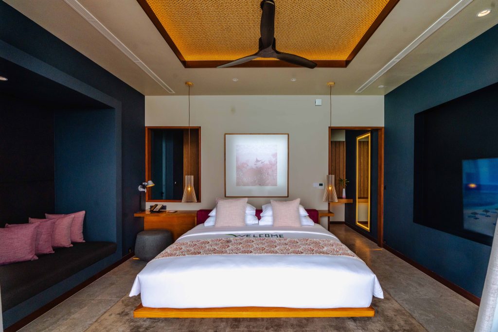 Modernes Zimmer der Ocean Pool Villa mit großem Doppelbett, blauen Wänden und Holzdecke im Veligandu Maldives Resort Island