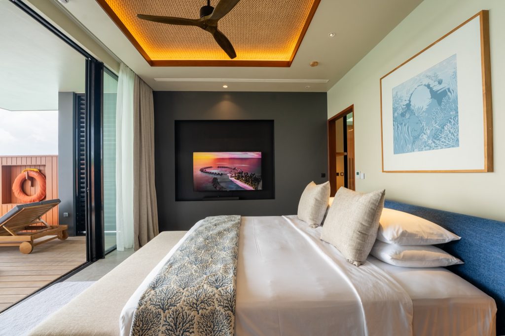 Modernes Hotelzimmer im Veligandu Maldives Resort Island mit großem Bett, Balkontür und natürlichem Licht