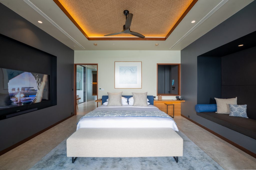 Modernes Hotelzimmer der Sunset Ocean Pool Villa mit großem Bett, Flachbildfernseher und gepolsterter Sitzgelegenheit