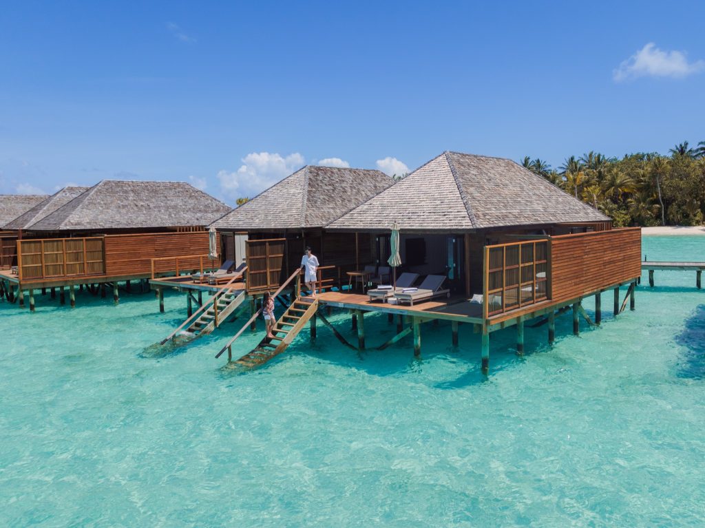 Überwasser-Bungalows aus Holz auf Stelzen über türkisblauem Ozean bei klarem Tageslicht