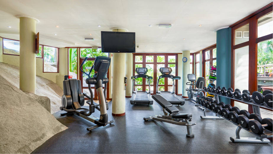 Heller Fitnessraum im DoubleTree Allamanda mit Hometrainern, Laufbändern, Hantelbank und großen Glasfenstern