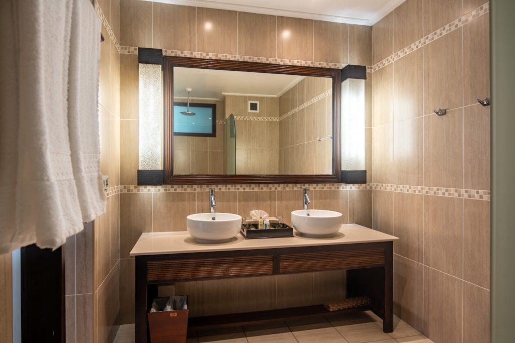 Modernes Badezimmer mit Doppelwaschbecken, großem Spiegel und beige gefliesten Wänden im deluxe ocean view Zimmer