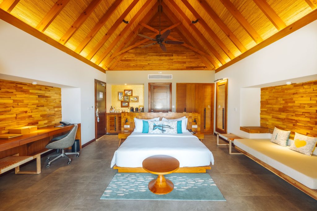 Geräumiges Zimmer der Beach Duplex Villa mit Holzbalkendecke, großem Bett, Schreibtisch und Sitzbereich