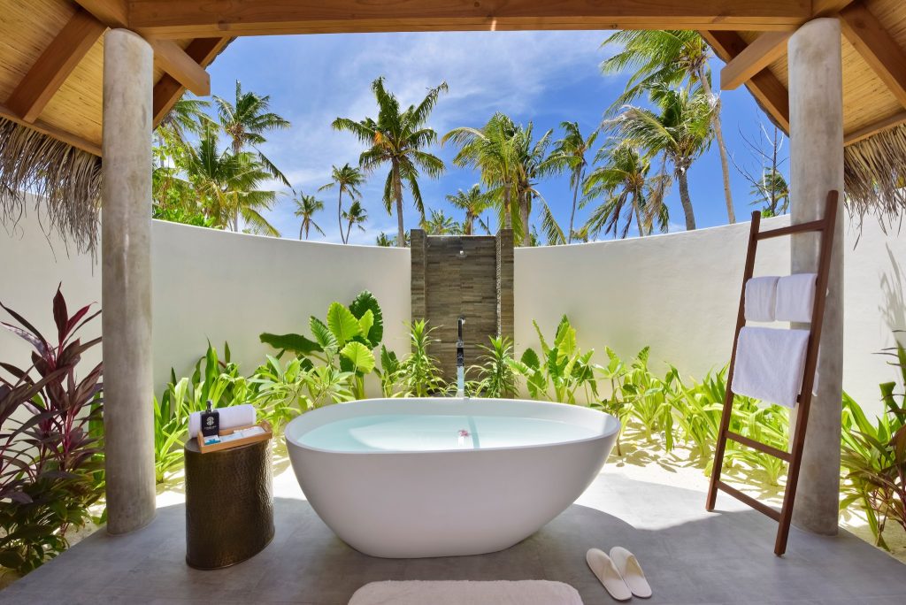 Offenes Badezimmer der Beach Villa im Fushifaru Maldives mit weißer freistehender Badewanne.