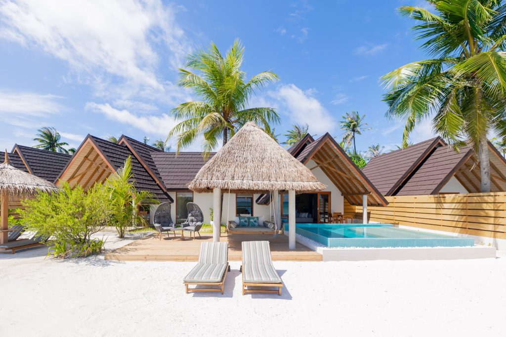 Terrasse der Premium Duplex Beach Villa mit Sonnenliegen, privatem Pool und strohgedeckten Bungalows auf den