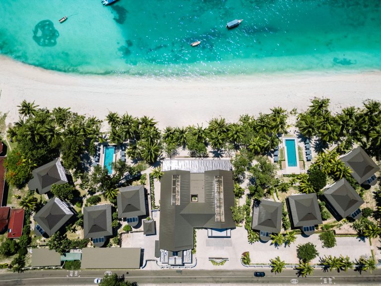Luftaufnahme der Indian Ocean Lodge auf den Seychellen mit Bungalows, zentralem Gebäude, Palmen und Strand