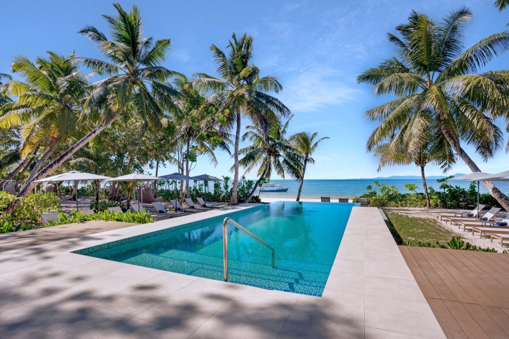 Infinity-Pool mit türkisfarbenen Mosaikfliesen, umgeben von Palmen