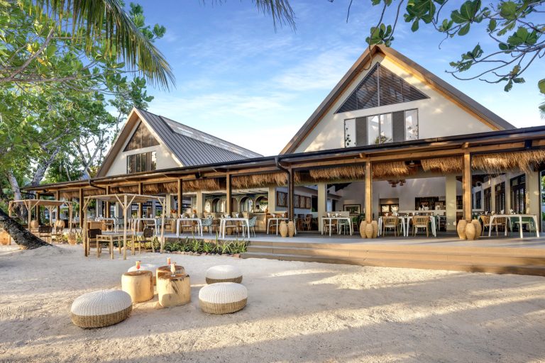 Offener Restaurantbereich Indian Ocean Lodge mit Strohdach, Holzmöbeln und Glaswänden bei Tageslicht