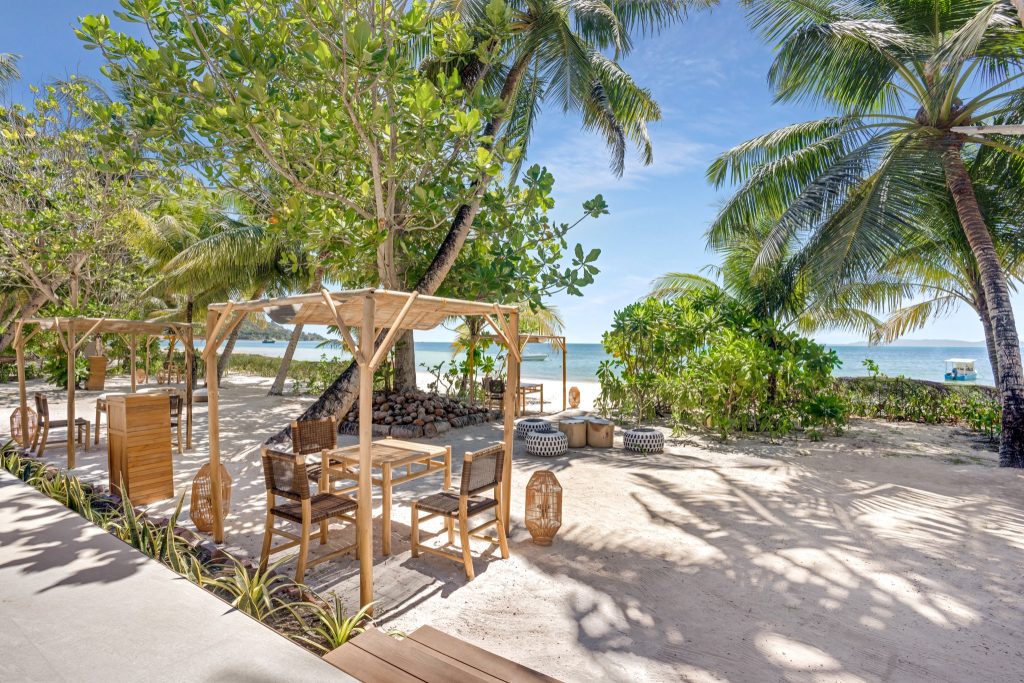 Strandrestaurant Kokosol Cabanas mit Holzmöbeln und Pergolen, Palmen und Meer im Hintergrund auf den