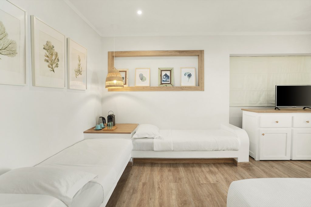 Helles Hotelzimmer Standard Sofa mit zwei Einzelbetten, Holzboden, botanischen Bildern und Hängelampe auf den