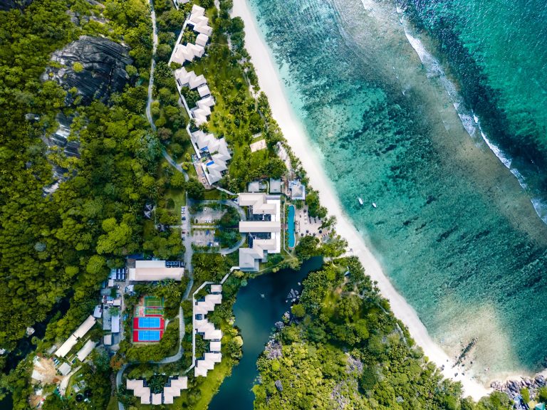 Luftaufnahme des Kempinski Seychelles Resort mit rechteckigen Gebäuden, Sandstrand und türkisfarbenem Meer