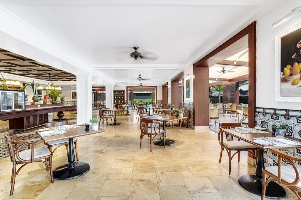Restaurant Café Lazare im Kempinski Seychelles Resort mit Holztischen, weißen Sitzauflagen und poliertem Steinboden