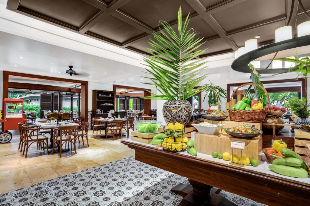 Innenraum des Restaurant Café Lazare im Kempinski Seychelles Resort mit Buffet, Holzmöbeln und großen Fenstern