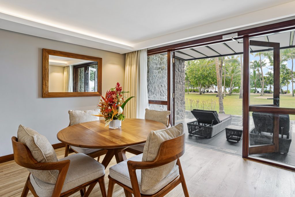 Zimmer der Plantation Suite mit Holztisch, gepolsterten Stühlen und Terrasse mit grünem Ausblick im Kempinski Seychelles.