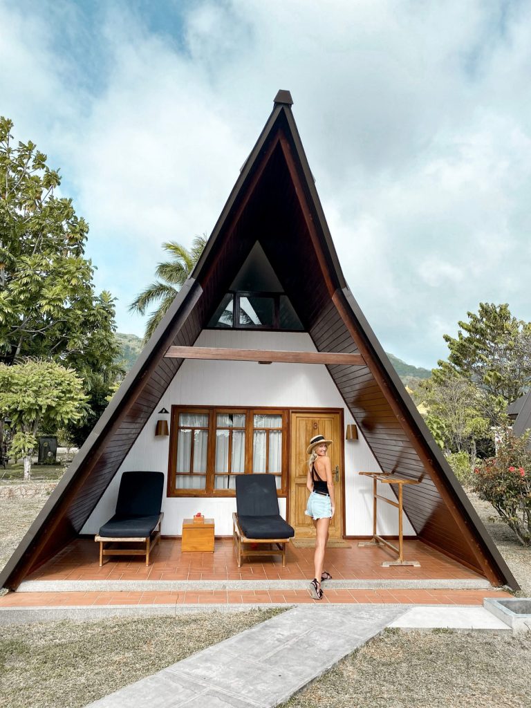 A-förmiges Beach Chalet aus Holz mit spitzem Dach, Terrasse mit Liegestühlen und Holztisch