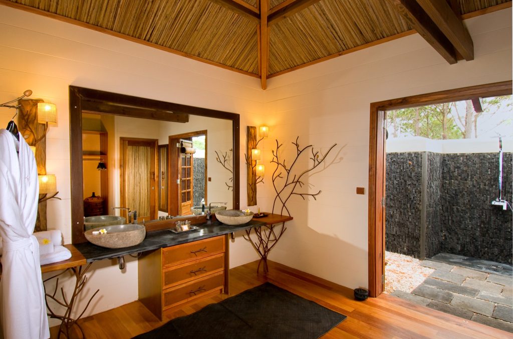 Badezimmer mit zwei runden Steinwaschbecken auf Holzkommode und Außendusche in deluxe-garden-room