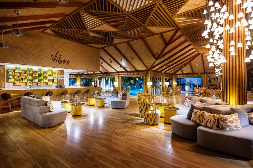 Moderne Bar im Lily Beach Resort & Spa mit Holzfußboden, Decke, grauen Sofas und gelben Tischen