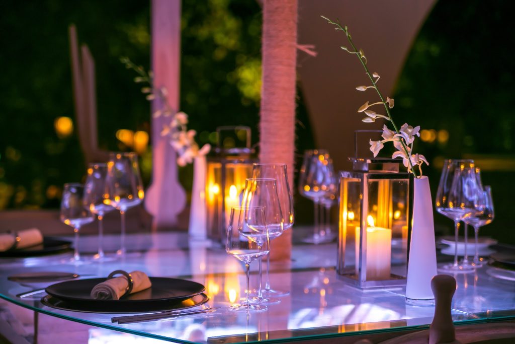 gedeckter Tisch im Restaurant Dhoni mit schwarzen Tellern, Stoffservietten, Weingläsern, weißen Vasen und Kerzenlicht