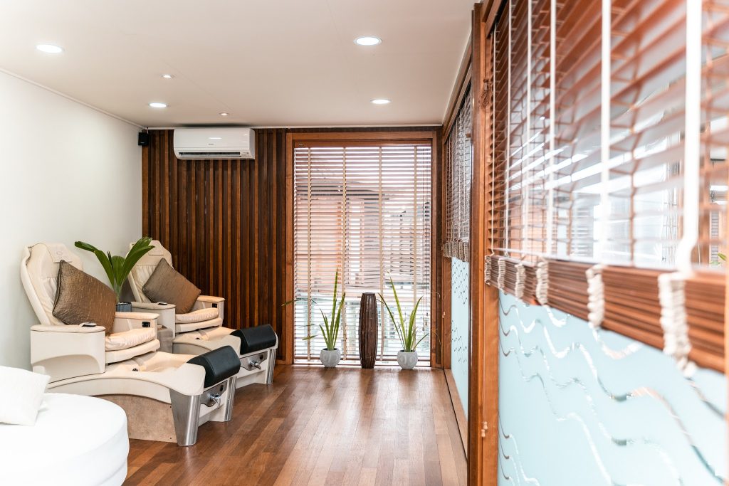 Wellnessbereich mit zwei beigen Massagesesseln, Holzboden, Pflanzen vor Fenster mit Jalousien im Tamara Spa