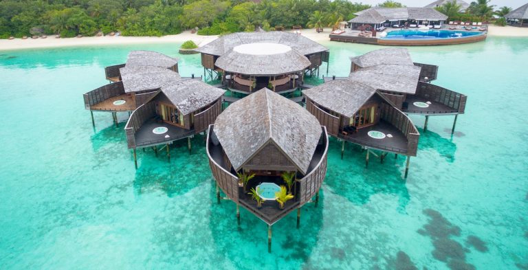 Über Wasser erbaute Holzbungalows mit Schindeldächern und privaten Jacuzzis, verbunden durch Stege, aufgenommen.