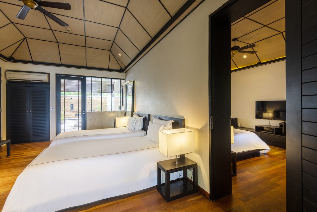 Modernes Hotelzimmer der Beach Family Villa mit zwei Einzelbetten, Doppelbett, Holzboden und großen Fenstern