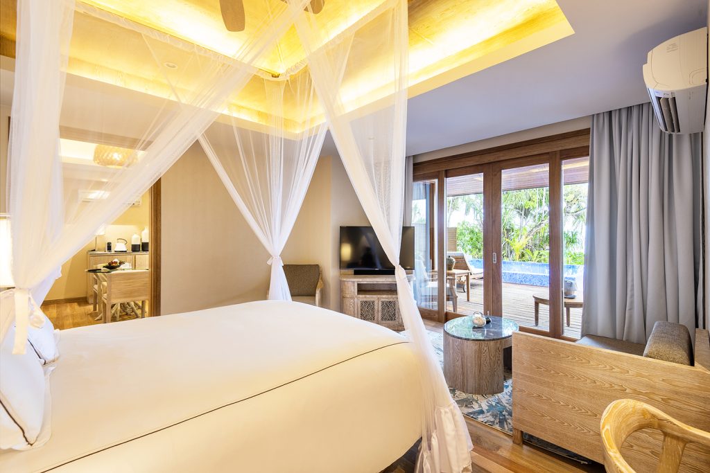 Hotelzimmer Beach Residence mit Himmelbett, Moskitonetz, Holzboden, Wohnzimmer und Terrasse mit Poolblick