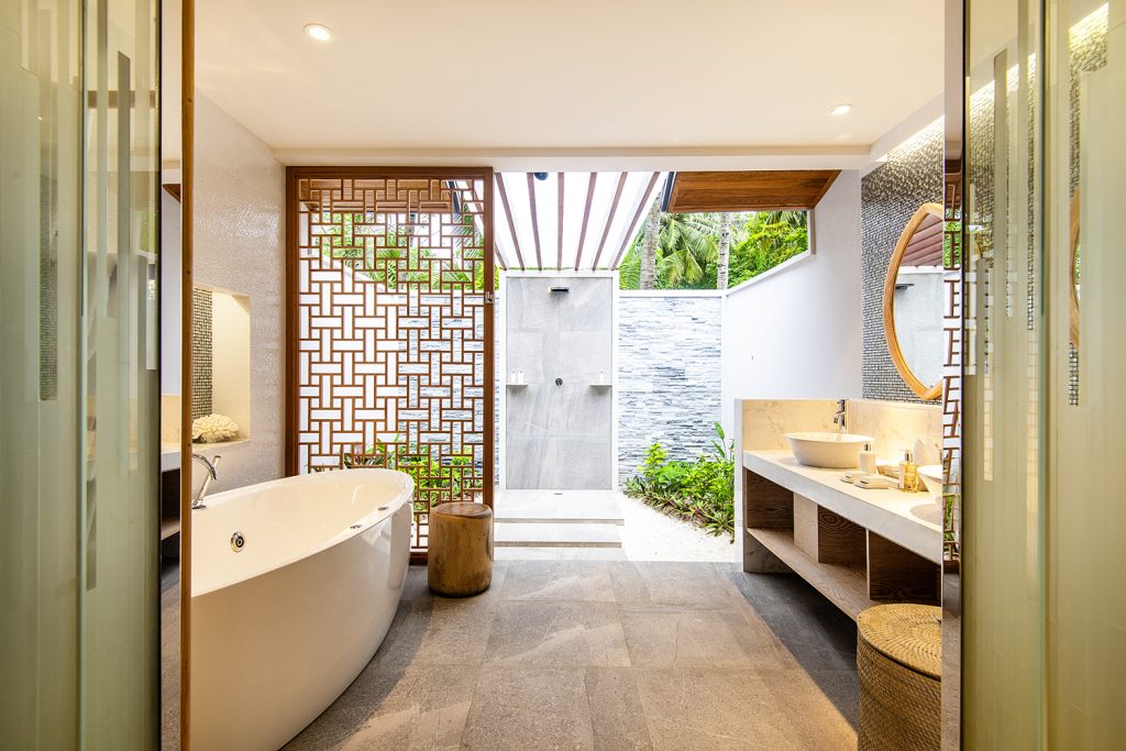 Modernes Badezimmer der Beach Suite im Lily Beach Resort & Spa mit freistehender Badewanne und Holzwand